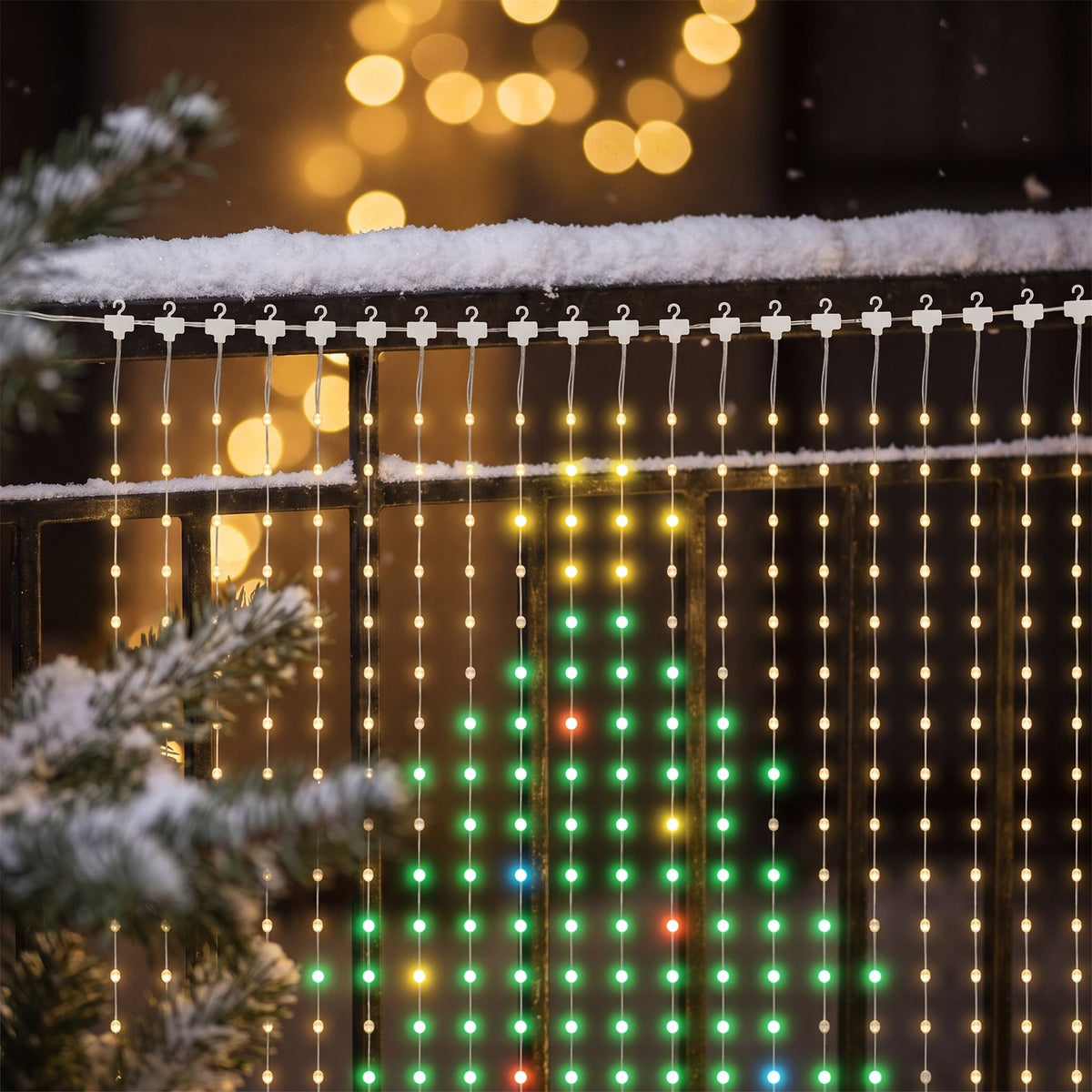 Close-up of the white hooks, thin wire strands and glowing LED beads on a snowy balcony railing
